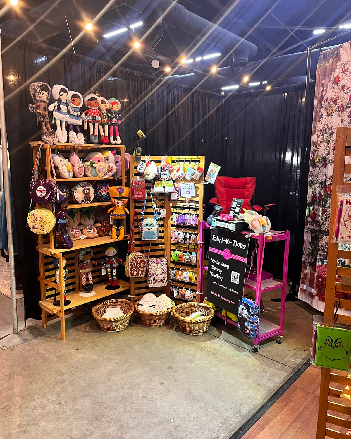 Indoor Fabri-K-Tions market booth under string lights with handmade dolls, bags and plushies