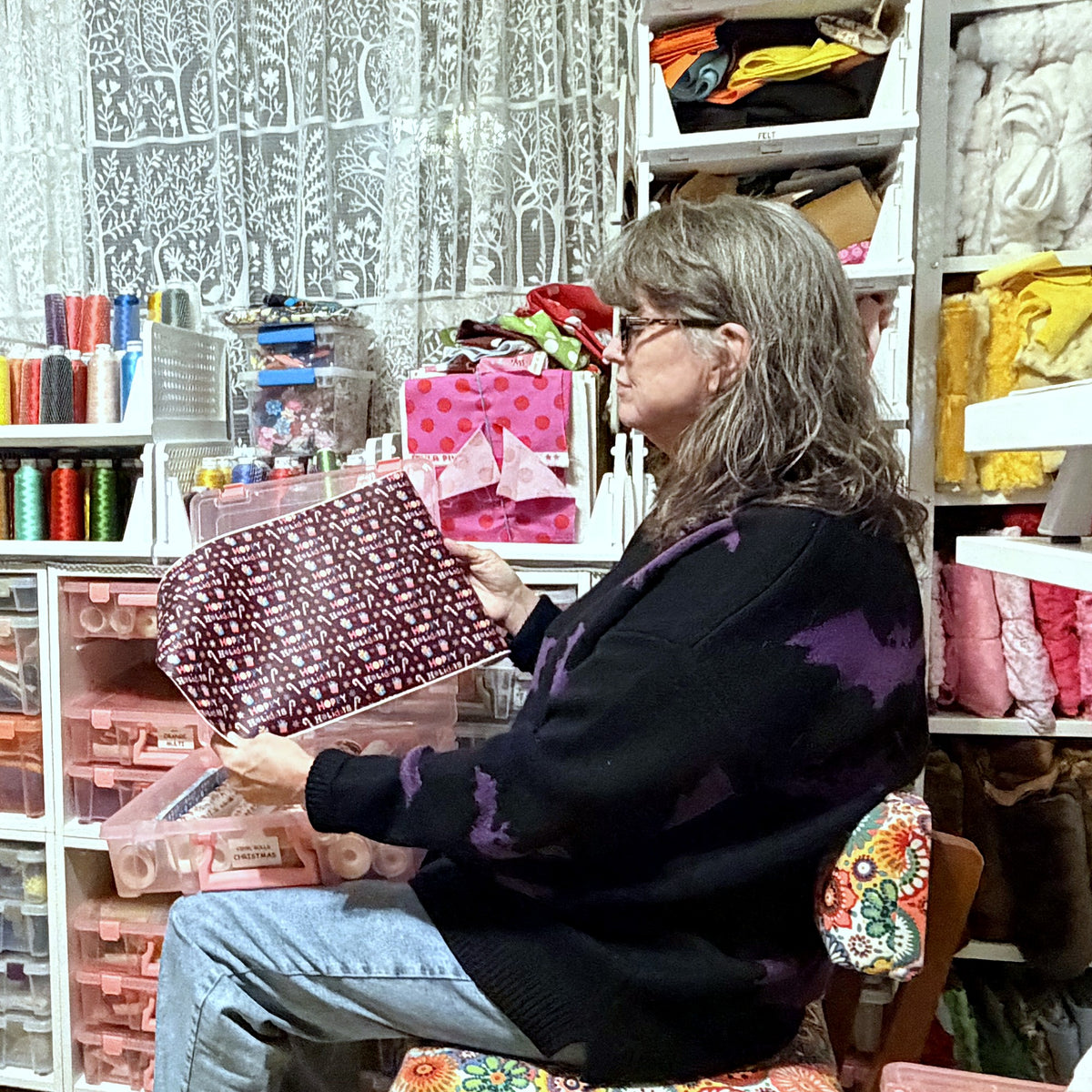 Kathy Creech looking over a finished handmade zipper pouch in her Louisville sewing room